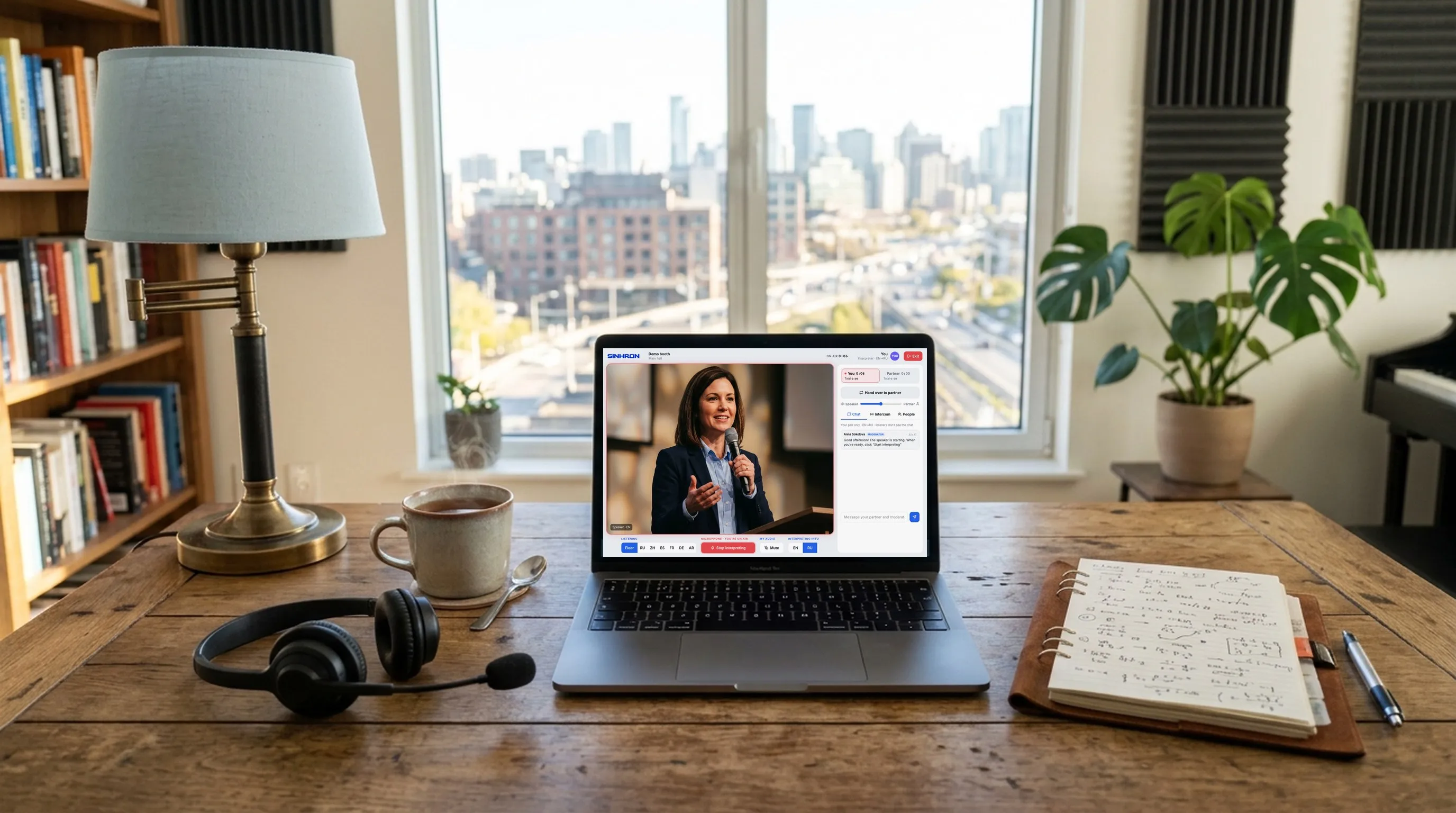 An interpreter's home workplace: a laptop with the SIMULTAN booth on air, a headset and a cup of tea